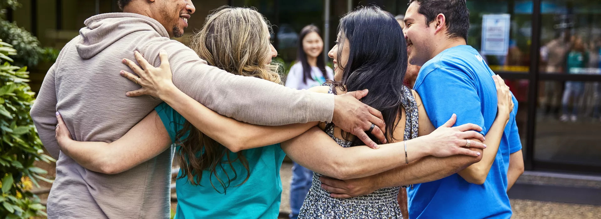 A group of four adults hugging and smiling