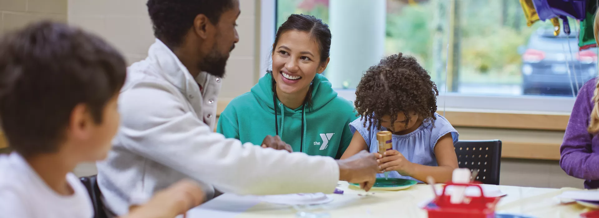 Y staff connects with a caregiver at an art table.